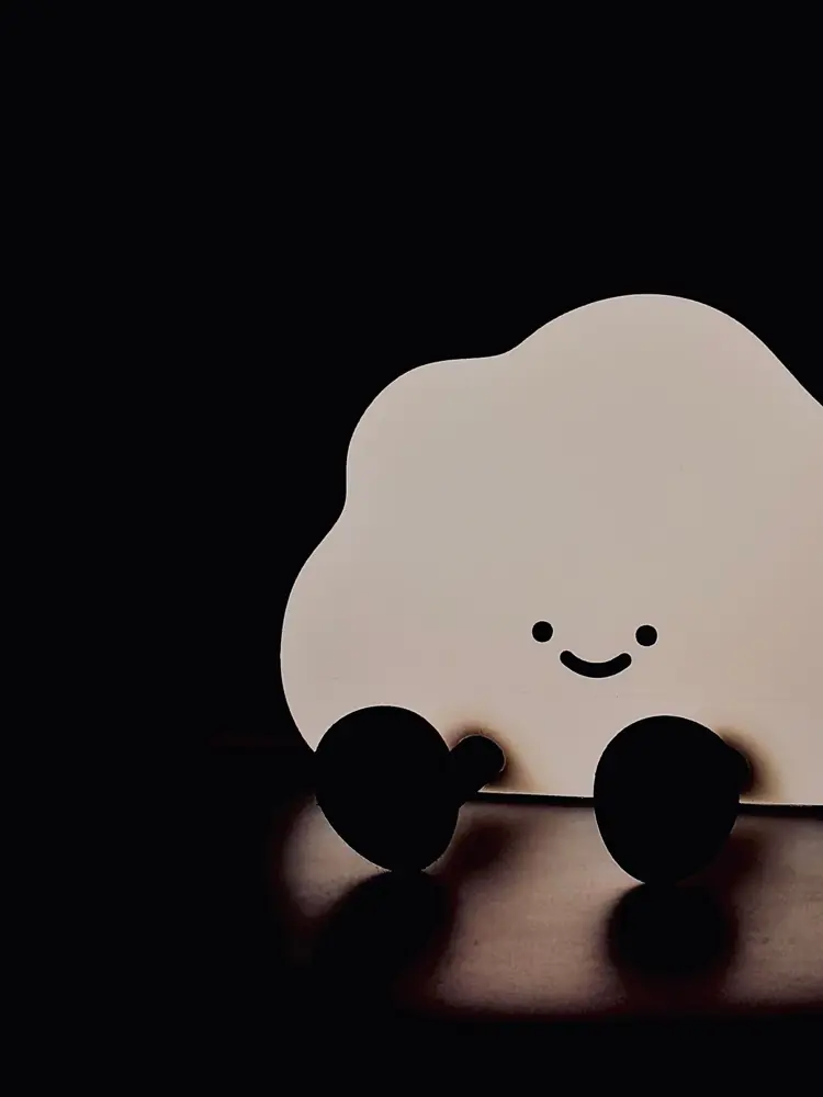 Smiling cloud lamp glowing in a dark room